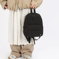 Minimalist black nylon mini backpack with adjustable straps held by a model - Black
