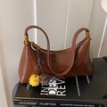 Braune glänzende Ledertasche in Melonenform mit Goldbeschlägen und Pelz-Anhänger-Dekor - Braun mit Anhänger