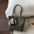 Detail of dark green suede tote bag with a cute plush bunny charm on white pillow - Green with Charm
