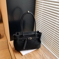Black tote bag with white contrast stitching and gold metal buckle on a wood surface - Black