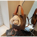 Detailed view of brown lychee leather bucket bag with orange handle and plush rabbit charm - With Pendant / Coffee