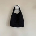 Dettaglio della borsa tote trapuntata nera con texture imbottita appesa a un gancio - Nero