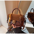 Dettaglio della borsa in pelle marrone retrò con chiusura a girello e perline in legno colorate - Caffè con Ciondolo