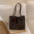Donkergrijze grote tote bag van mat leer met bruine pluchen hanger op witte bank - Koffie met Hanger