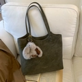 Olive green leather tote bag with plush rabbit charm displayed on a white sofa - Green with Pendant