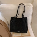 Minimalist black leather tote bag with slim shoulder straps shown on a white sofa - Black without Pendant
