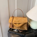 Retro Handtasche aus kamelfarbenem Wildleder mit goldenem Drehverschluss auf Büchern - Braun
