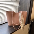 Bolso tote rosa de cuero granulado con cinta de moda sobre un alféizar de madera - Rosa