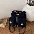 Dettaglio dello zaino in pelle scamosciata trapuntata nera con catene d'oro sul legno - Nero