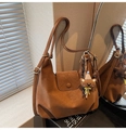 Sac bandoulière en cuir marron avec breloque ours et pompons vu dans un miroir de salon - Marron avec pendentif