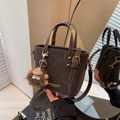 Dark brown mini bucket tote bag with plush monster charm and top handles in mirror reflection - Coffee with Pendant