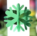 Close-up of a bright green metallic snowflake napkin ring on a white paper roll - Reflective Green