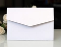 Dettaglio di busta in carta perlata bianca con lembo a V e decorazione floreale - Bianco