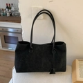 Borsa tote minimalista nera in finta pelle scamosciata con spalline sottili sul divano - Nero