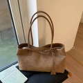 Dettaglio della borsa tote in pelle scamosciata marrone con cuciture e ciondolo decorativo - Cammello
