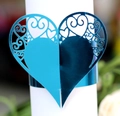 Close-up of heart-shaped laser-cut blue napkin ring with elegant scroll patterns - Reflective Blue