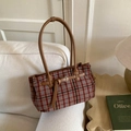 Dettaglio borsa tote in tartan rosso e blu con manici in pelle marrone su un divano - Tartan Rosso