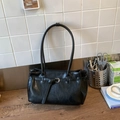 Dettaglio di una borsa tote grande in pelle nera con cinturini e lunghi manici sottili - Nero