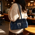 Deep blue denim Boston bag with large silver buckle shown on a female model shoulder - Dark Blue
