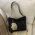 Borsa hobo nera vintage con cuciture bianche e ciondolo orsetto su divano beige - Nero con ciondolo