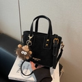 Matte schwarze Beuteltasche mit runden Griffen und süßem Monster-Anhänger-Detail - Mit Anhänger / Schwarz