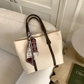Detail of cream and brown tote bag with decorative silk scarf on minimalist sofa - Off White