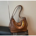 Detail der braunen Hobo-Tasche mit Holzperlenanhänger und geprägtem Lederetikett - Braun