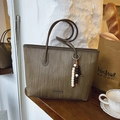 Bolso tote tejido en tonos tierra con correas finas y un adorno de cuentas sobre madera - Verde