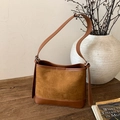 Detailed view of caramel brown suede tote on a rustic wooden table with vintage props - Brown