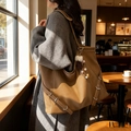 Grande borsa tote in pelle kaki con ciondolo a pompon in peluche in un ambiente accogliente - Con Ciondolo / Marrone