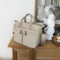 Close-up of cream nylon tote bag with dual metal ring zippers and adjustable straps - Off White