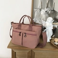 Detail view of pink waterproof nylon tote bag showing front zip pockets and wide straps - Dusty Pink