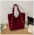 Macro shot of dark burgundy suede tote bag with stylish silver studs on long handles - Burgundy