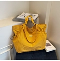 Detalle del bolso tote amarillo jengibre con textura de nailon y asa de nudo decorativa - Amarillo