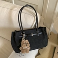 Black matte suede tote bag with leather handles and a plush bear pendant on a sofa - Black