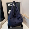 Detail of dark blue nylon tote bag showing front pocket and wrinkled texture fabric - Blue