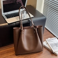 Minimalistische große braune Leder-Shopper-Tasche mit Nieten-Griffen im Büro-Ambiente - Kaffeebraun