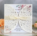 Detail of ivory laser-cut floral wedding invitation with an elegant silk ribbon bow - Ivory