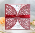 Close-up of laser-cut burgundy wedding card with floral patterns and silk ribbon bow - Dark Red