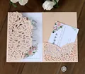 Detail view of laser-cut rose hollow invitation with floral RSVP card set on dark wood - Pink