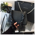 Detail of black quilted shoulder bag with ruffles and glossy leather texture - Black