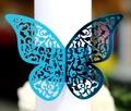 Macro view of blue laser-cut butterfly napkin ring with intricate vine textures - Reflective Blue