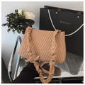 Close-up of caramel quilted bag with pleated strap next to a gift bag with pearl handles - Brown