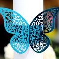 Laser-cut peacock blue butterfly napkin ring with intricate vine patterns for weddings - Reflective Blue