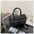 Detail view of black leather Boston bag with silver hardware on office desktop setup - Black