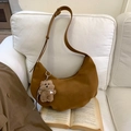 Close-up of brown crescent hobo bag with a cute bear charm on a soft white sofa - Brown with Pendant