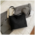 Détail d'un sac à bandoulière noir en daim minimaliste sur un tissu de costume gris - Noir