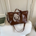 Vintage dark brown tote bag in oil wax leather with cute grey bunny charm on white sofa - Brown with Pendant