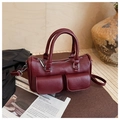 Detalle del bolso cilíndrico burdeos con dos bolsillos frontales y cremalleras plateadas - Rojo