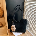 Elegante schwarze Tragetasche mit Hundianhänger und Perlenkette auf einem Holztisch - Schwarz mit Anhänger